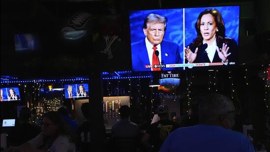 People watch TV screens showing a debate between Democratic presidential nominee Vice President Kamala Harris, right, and Republican presidential nominee former President Donald Trump, at Sports Grill Kendall, where the Miami-Dade Democratic Hispanic Caucus had organized a watch party, on Sept. 10 (AP FILE PHOTO)