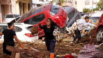 Residents clean the street next to cars piled up after being swept away by floods in Valencia, Spain. (AP) Residents clean the street next to cars piled up after being swept away by floods in Valencia, Spain. (AP)