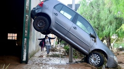 A resident walks next to a car lifted up in a street covered in mud in a flooded area in Picanya. (AFP) A resident walks next to a car lifted up in a street covered in mud in a flooded area in Picanya. (AFP)