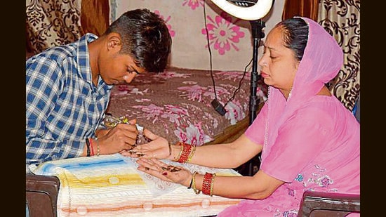17-year old Vijay Kumar applies henna on a woman’s hand in Ludhiana on Wednesday. (Manish/HT)
