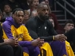 Los Angeles Lakers guard Bronny James, left, and forward LeBron James, right, watch from the bench in the first half of an NBA basketball game against the Cleveland Cavaliers. Los Angeles Lakers guard Bronny James, left, and forward LeBron James, right, watch from the bench in the first half of an NBA basketball game against the Cleveland Cavaliers.