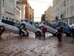 Residents walk past piled up cars following deadly floods in Valencia's De La Torre neighbourhood, south of Valencia, eastern Spain, on October 30, 2024. Residents walk past piled up cars following deadly floods in Valencia's De La Torre neighbourhood, south of Valencia, eastern Spain, on October 30, 2024.