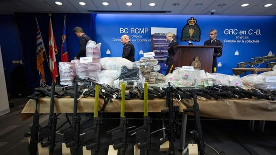 Firearms and illicit drugs seized last week are displayed as Royal Canadian Mounted Police Chief Supt. Stephen Lee, back from left, Asst. Commissioner David Teboul, Insp. Jillian Wellard and Cpl. Arash Seyed leave after a news conference at RCMP headquarters, in Surrey, British Columbia, (AP)