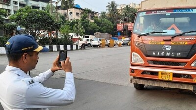 A traffic police personnel seen  issuing e-challan to a heavy vehicle near Mulund Toll Naka. (Praful Gangurde/HT Photo) (HT PHOTO)