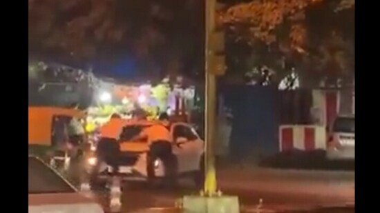 Screengrab from the video shows two police personnel holding the car's bonnet while the driver carries them around for a fair distance. (@payal_mohindra/ X)