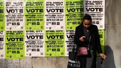 A woman waits for the bus before a wall covered with posters encouraging people to vote in Pittsburgh, Pennsylvania, on November 4, 2024, one day before the US presidential election. (Photo by Charly TRIBALLEAU / AFP) (AFP)