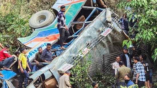 Police personnel and people gather near the bus that fell into a gorge near Marchula claiming the lives of 23 people, in Almora on Monday. (ANI)