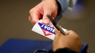 A poll worker hands a voter an 'I Voted' sticker at a polling booth in Nevada. (Bloomberg) A poll worker hands a voter an 'I Voted' sticker at a polling booth in Nevada. (Bloomberg)