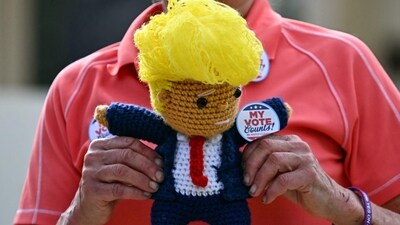A supporter of US President and Republican presidential candidate Donald Trump holds a knitted doll of Trump outside the polling station at Mandel Recreation Centre before Trump arrives to vote in Palm Beach, Florida, on Election Day, November 5, 2024. (Photo by CHANDAN KHANNA / AFP) (AFP) A supporter of US President and Republican presidential candidate Donald Trump holds a knitted doll of Trump outside the polling station at Mandel Recreation Centre before Trump arrives to vote in Palm Beach, Florida, on Election Day, November 5, 2024. (Photo by CHANDAN KHANNA / AFP) (AFP)