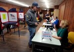 A voter, center, receives assistance from a poll worker before voting on Election Day in Waltham, US.