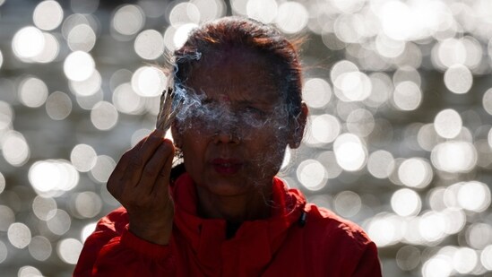 A Nepalese woman offers prayers to the setting sun on the bank of Bagmati River during the Chhath Puja festival in Kathmandu.(AP)