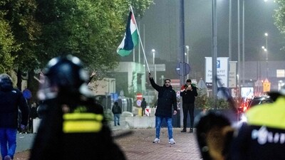 A supporter waves a Palestinian flag in front of Police officers from Mobile Unit (ME) during a pro-Palestinian demonstration on the sideline of the UEFA Europa League football match between Ajax Amsterdam and Maccabi Tel Aviv, in Amsterdam on November 7, 2024. (Photo by Jeroen Jumelet / ANP / AFP) / Netherlands OUT (AFP) A supporter waves a Palestinian flag in front of Police officers from Mobile Unit (ME) during a pro-Palestinian demonstration on the sideline of the UEFA Europa League football match between Ajax Amsterdam and Maccabi Tel Aviv, in Amsterdam on November 7, 2024. (Photo by Jeroen Jumelet / ANP / AFP) / Netherlands OUT (AFP)