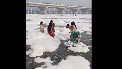 In a viral video, a woman was seen bathing in the Yamuna even as a toxic foam floating around her. (X/@mrjethwani_) In a viral video, a woman was seen bathing in the Yamuna even as a toxic foam floating around her. (X/@mrjethwani_)