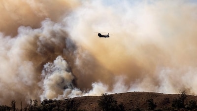 CORRECTION / TOPSHOT - A fire helicopter flies toward the Mountain Fire�s plume as it scorches acres, the wildfire fueled by strong Santa Ana winds, in Moorpark, California, on November 7, 2024. Thousands of people were urged to flee an out-of-control wildfire burning around communities near Los Angeles on November 7, with scores of homes already lost to the fast-moving flames.
Fierce seasonal winds had cast embers up to three miles (five kilometers) from the seat of the fire around Camarillo, with new spots burning on hillsides, farmland and in residential areas. (AFP)
