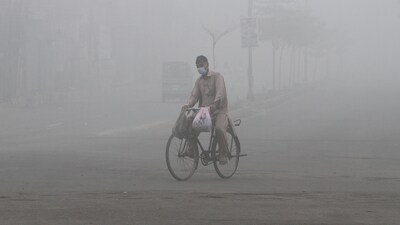 A man wears a mask to avoid smog while he rides on a bicycle along a road in Multan (REUTERS)