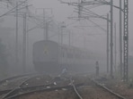 Men wait on a railway track as a train passes by, on a smoggy morning in New Delhi, on November.