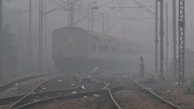 Men wait on a railway track as a train passes by, on a smoggy morning in New Delhi, on November.