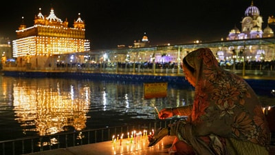 A devotee lights a candle at Golden Temple on Guru Nanak Jayanti, in Amritsar, in 2023 (PTI) A devotee lights a candle at Golden Temple on Guru Nanak Jayanti, in Amritsar, in 2023 (PTI)