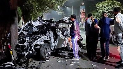 People gather around the car that got mangled after it got hit by a container, in Dehradun on Monday. At least six people were killed and one other was injured in the accident. (ANI Photo) (ANI) People gather around the car that got mangled after it got hit by a container, in Dehradun on Monday. At least six people were killed and one other was injured in the accident. (ANI Photo) (ANI)