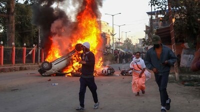 People run past burning vehicles of India's Bharatiya Janata Party (BJP) MLA during a protest to condemn the alleged killing of women and children in Imphal, capital of India's violence-hit northeastern state of Manipur on November 16, 2024. (Photo by AFP) (AFP)