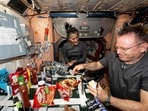 NASA astronauts Suni Williams and Butch Wilmore, both Expedition 71 Flight Engineers, make pizza aboard the International Space Station's galley located inside the Unity module on Sept. 9, 2024. Items are attached to the galley using tape and velcro to keep them from flying away in the microgravity environment. 