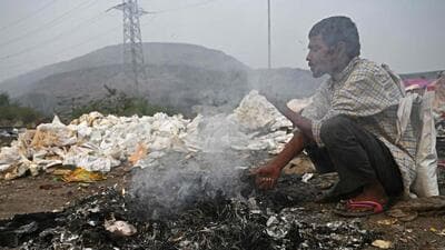 A man burns waste near Ghazipur landfill to keep himself warm in the early hours of Tuesday. (AFP) A man burns waste near Ghazipur landfill to keep himself warm in the early hours of Tuesday. (AFP)