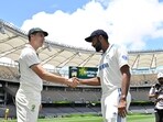 Australia'ss captain Pat Cummins (L) shakes hands with India's captain Jasprit Bumrah after posing with the trophy.