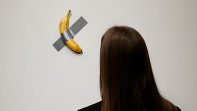 People look at Italian visual artist Maurizio Cattelan's duct-taped Banana titled Comedian. (AFP)