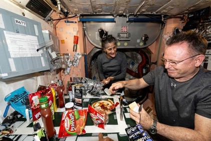 In this image released by NASA, NASA astronauts Suni Williams and Butch Wilmore, both Expedition 71 Flight Engineers, make pizza aboard the International Space Station's galley located inside the Unity module on Sept. 9, 2024. Items are attached to the galley using tape and velcro to keep them from flying away in the microgravity environment. (AP) In this image released by NASA, NASA astronauts Suni Williams and Butch Wilmore, both Expedition 71 Flight Engineers, make pizza aboard the International Space Station's galley located inside the Unity module on Sept. 9, 2024. Items are attached to the galley using tape and velcro to keep them from flying away in the microgravity environment. (AP)