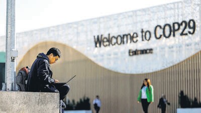 A man uses his laptop as he sits near the COP29 United Nations climate change conference pavilion, in Baku, Azerbaijan, on Friday. (REUTERS) A man uses his laptop as he sits near the COP29 United Nations climate change conference pavilion, in Baku, Azerbaijan, on Friday. (REUTERS)