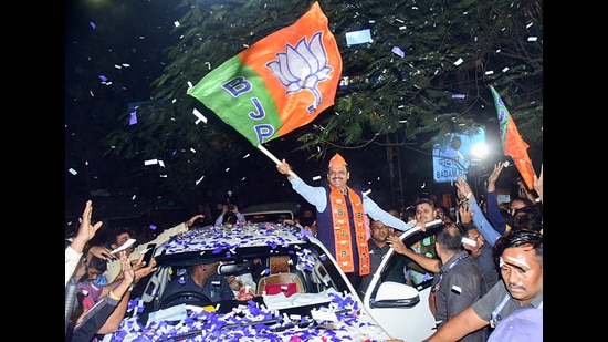 Maharashtra deputy chief minister and BJP candidate Devendra Fadnavis waves the party's flag as he arrives to collect his winning certificate from the Nagpur South West Constituency, in Nagpur on Saturday. (ANI)