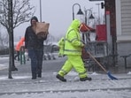 A worker clears snow as last-minute grocery shoppers leave a Market Basket supermarket  during a fast-moving winter storm which was expected to hit the U.S. Northeast, in Plymouth, Massachusetts, U.S.February 13, 2024.