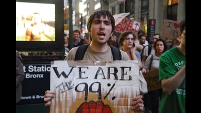 A man holding a sign that says, “We Are The 99%” at an Occupy Wall Street protest. Rumaan Alam’s ‘Entitlement’ is set in the wake of the Occupy Wall Street Movement. (Wikimedia Commons) A man holding a sign that says, “We Are The 99%” at an Occupy Wall Street protest. Rumaan Alam’s ‘Entitlement’ is set in the wake of the Occupy Wall Street Movement. (Wikimedia Commons)