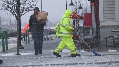 A worker clears snow as last-minute grocery shoppers leave a Market Basket supermarket  during a fast-moving winter storm which was expected to hit the U.S. Northeast, in Plymouth, Massachusetts, U.S.February 13, 2024. (REUTERS / Ken McGagh)