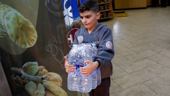 A boy carries water bottles to the car on his way back to southern Lebanon, in Sidon.(REUTERS)