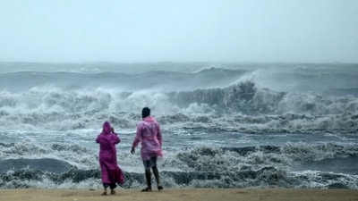People stand ashore as they observe waves amidst heavy winds and rainfall at Marina Beach in Chennai on November 30, 2024, ahead of the landfall of cyclone Fengal in Tamil Nadu. (AFP) People stand ashore as they observe waves amidst heavy winds and rainfall at Marina Beach in Chennai on November 30, 2024, ahead of the landfall of cyclone Fengal in Tamil Nadu. (AFP)
