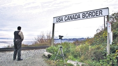 A Canadian Customs and Fisheries officer watches over the US-Canada border between Blaine, Washington and White Rock, British Columbia. (Getty Images) A Canadian Customs and Fisheries officer watches over the US-Canada border between Blaine, Washington and White Rock, British Columbia. (Getty Images)