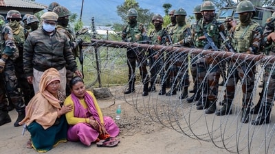 Family members sit in protest as army personnel stand guard at a checkpoint during a demonstration after a man from the Meitei community who worked at the camp allegedly remained missing, in Imphal West on November 30, (AFP) (AFP) Family members sit in protest as army personnel stand guard at a checkpoint during a demonstration after a man from the Meitei community who worked at the camp allegedly remained missing, in Imphal West on November 30, (AFP) (AFP)