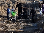 A woman reacts next to a temporary grave of a relative, as a civil defence member removes bodies of people killed during hostilities between Israel and Hezbollah in Tyre, southern Lebanon on December 2. (REUTERS) 