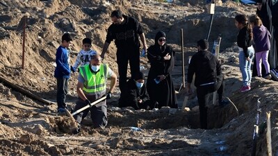 A woman reacts next to a temporary grave of a relative, as a civil defence member removes bodies of people killed during hostilities between Israel and Hezbollah in Tyre, southern Lebanon on December 2. (REUTERS) (REUTERS)