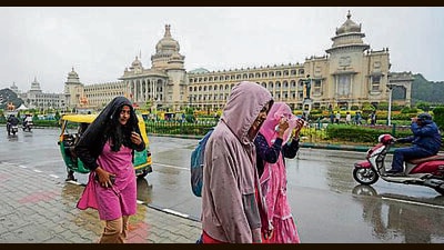People walk in the rain near Vidhanasoudha in Bengaluru. (PTI) People walk in the rain near Vidhanasoudha in Bengaluru. (PTI)