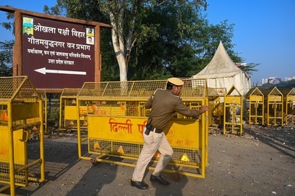 A cop puts up barricades near the Okhla bird sanctuary ahead of the farmers march. (Sunil Ghosh/HT Photo) A cop puts up barricades near the Okhla bird sanctuary ahead of the farmers march. (Sunil Ghosh/HT Photo)