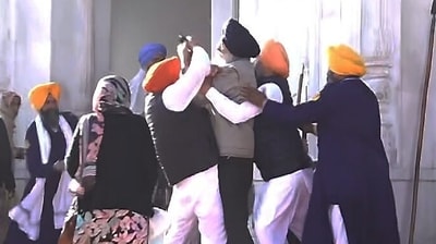 People catch a man who allegedly opened fire at Shiromani Akali Dal leader Sukhbir Singh Badal while the latter was serving the 'tankhah' (religious punishment) given by the Akal Takht at the Golden Temple, in Amritsar, Wednesday,