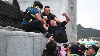 TOPSHOT - Police officers try to move South Korean protesters as they occupy the bronze statue of Admiral Yi Sun-shin, who won a major naval victory over Japan in the 16th century, during a protest against a visit of Japan's Prime Minister Fumio Kishida in Seoul (AFP) TOPSHOT - Police officers try to move South Korean protesters as they occupy the bronze statue of Admiral Yi Sun-shin, who won a major naval victory over Japan in the 16th century, during a protest against a visit of Japan's Prime Minister Fumio Kishida in Seoul (AFP)