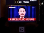 People watch a TV screen broadcasting a news report on South Korean President Yoon Suk Yeol's declaration of martial law. 