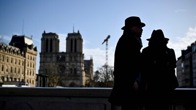 Pedestrians look at the Notre Dame de Paris cathedral on the eve of its official reopening on December 6, 2024, after more than five years of reconstruction work following the April 15, 2019 fire in Paris.&nbsp; (AFP)