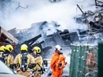 Firemen stand next to a partially collapsed residential building following a fire and an explosion in The Hague on December 7.