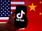 TikTok logo is displayed on the screen of an iPhone in front of a US flag and Chinese flag background in Washington, DC.