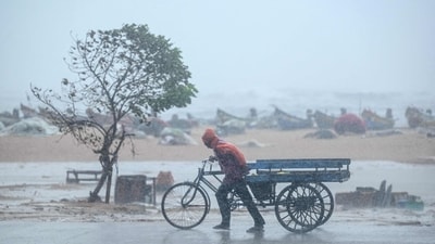 A man pulls his three-wheeler cart amid heavy wind and rainfall at the Marina Beach in Chennai. (File) (AFP)