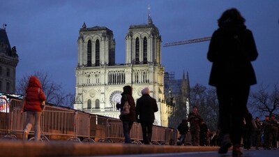 People walk past as France's iconic Notre Dame Cathedral is reflected in a puddle Saturday, Dec. 7, 2024 in Paris before the formal reopening for the first time since a devastating fire nearly destroyed the 861-year-old landmark in 2019. (AP)